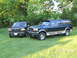 1995 Ford C-350 (Centurion Conversions) - Two green Ford SUVs, a C-350 Centurion Conversions and another model, are parked on a grassy lawn with trees in the background.