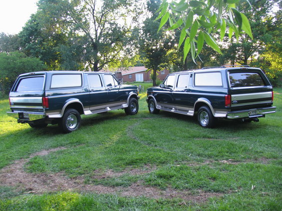 Two dark green Ford Bronco Centurion SUVs parked on grass, one angled towards the viewer