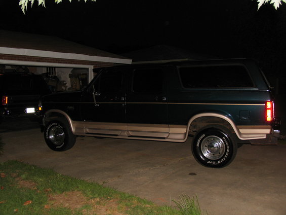 Side view of a 1995 Ford C-350 Centurion Conversions SUV in dark green and tan