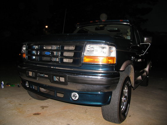 Dark teal Ford truck front view, grille and headlights visible