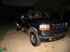 1995 Ford C-350 (Centurion Conversions) - This dark green SUV with tan trim is seen from a 3/4 front angle, showing the Ford grille.