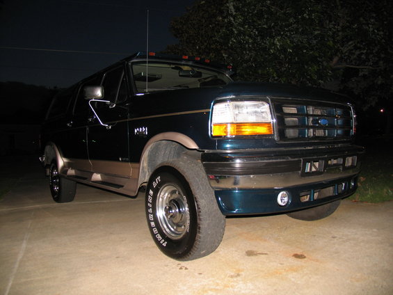 1995 Ford Bronco, dark green with tan lower trim, parked on concrete at night