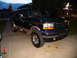 1995 Ford C-350 (Centurion Conversions) - This dark green SUV, likely a Centurion conversion, is seen from a three-quarter front view on a paved surface.