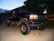 1995 Ford C-350 (Centurion Conversions) - Dark green 1995 Ford C-350 (Centurion Conversions) truck parked outside at twilight.