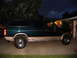 1995 Ford C-350 (Centurion Conversions) - A dark green Ford Bronco with tan trim is parked in a driveway at dusk, with a house and garage in the background.