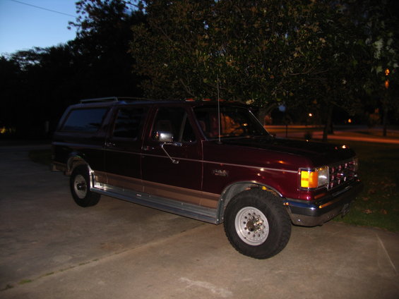 Maroon Ford Bronco Centurion with tan lower trim and roof rack, parked on concrete