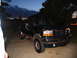 1995 Ford C-350 (Centurion Conversions) - A dark green Ford Bronco is parked on a concrete driveway as dusk settles.