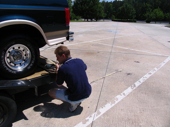 Dark green van with tan trim, side view, being loaded onto a trailer