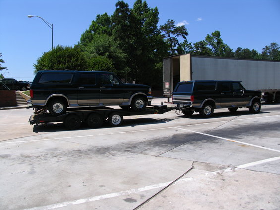 Two black Ford Broncos, one on a trailer being towed by the other
