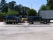 1995 Ford C-350 (Centurion Conversions) - Two dark green Ford Bronco SUVs are parked in a lot, one is on a trailer.