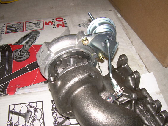 Turbocharger assembly with wastegate actuator. Some text visible on parts and packaging
