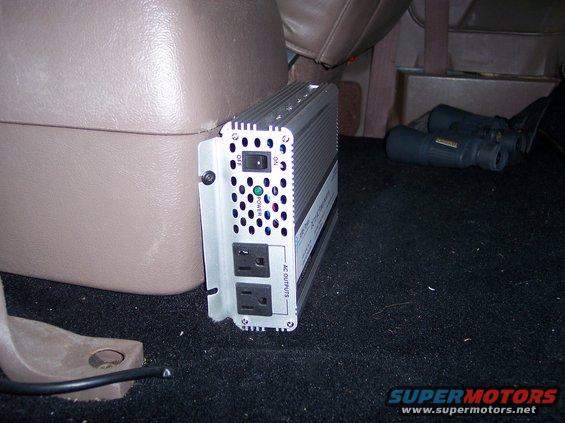 Power inverter and binoculars on carpeted floor inside a vehicle