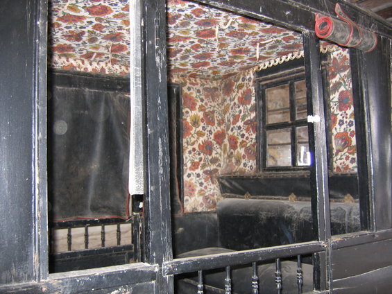 Interior of a horse-drawn carriage with floral wallpaper and dark upholstered seats