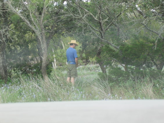 Man in straw hat and shorts urinating outdoors