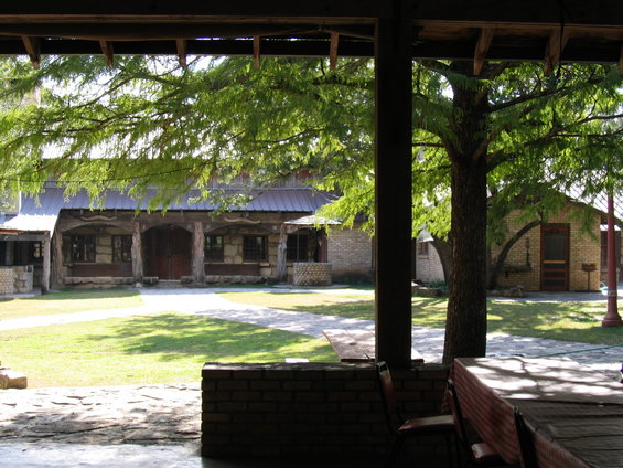 Building with stone and wood facade and metal roof, surrounded by green lawn and trees