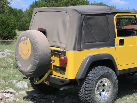 Yellow Jeep Wrangler rear view with spare tire cover showing a smiley face and text