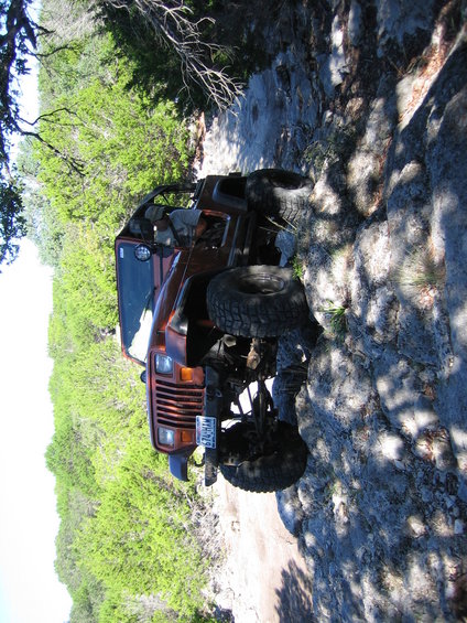Orange Jeep Wrangler off-roading on a rocky trail
