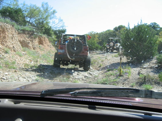 Two off-road vehicles on a rocky trail, one red and one white