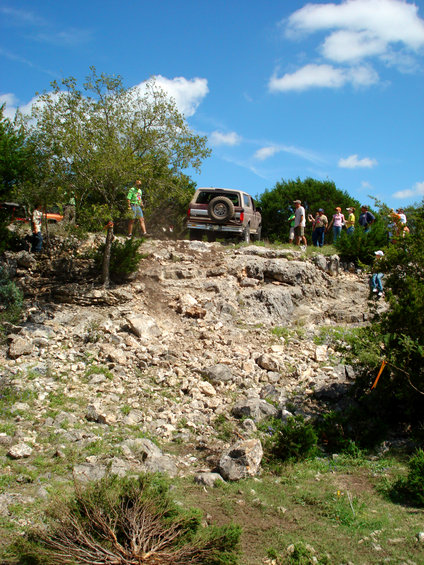 Brown 1996 Ford Bronco driving up a rocky hill, rear view