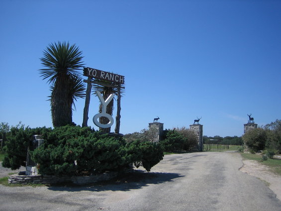 Yo Ranch entrance sign with yucca trees and stone pillars topped with animal statues