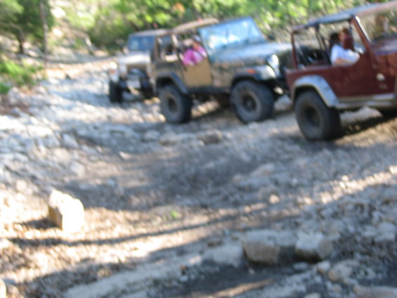 Three Jeeps driving on a rocky, off-road trail