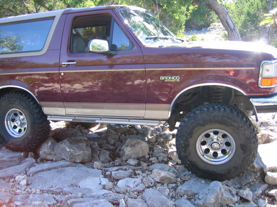 Maroon Ford Bronco with off-road tires navigating rocky terrain