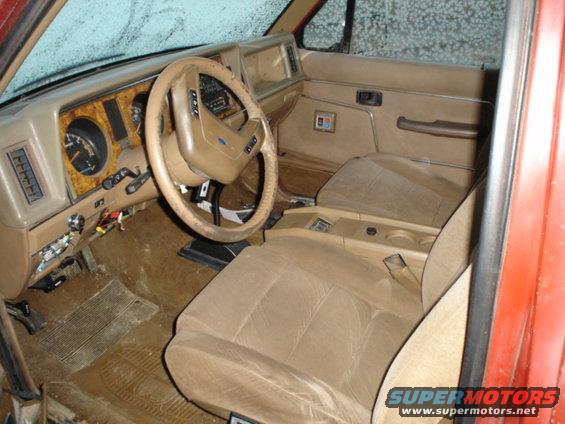 Tan interior of a 1980s SUV, showing dashboard, steering wheel, and seats