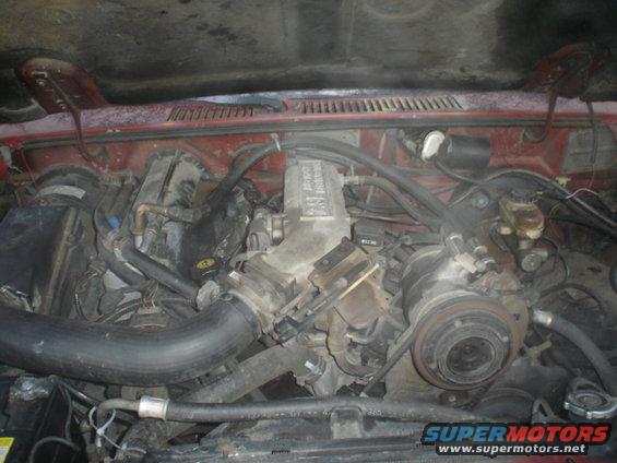 1986 Ford Bronco II engine bay, red exterior, cluttered with hoses and components