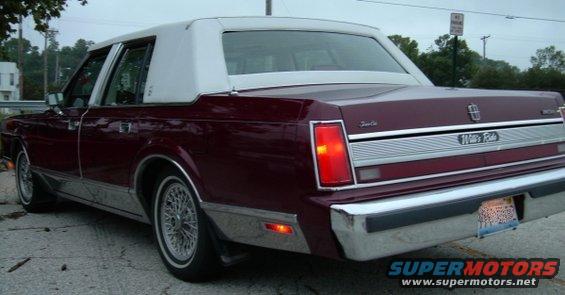 Maroon 1989 Lincoln Town Car, rear 3/4 view, white vinyl roof, 'Town Car' and 'Wellesley' badging visible
