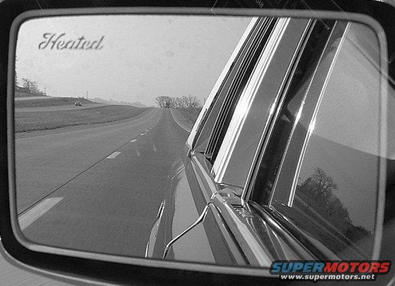 Side mirror shows a highway with another car in the distance. Text on mirror reads 'Heated'