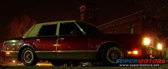 Maroon 1989 Lincoln Town Car with a white vinyl roof, seen from the front-right at night