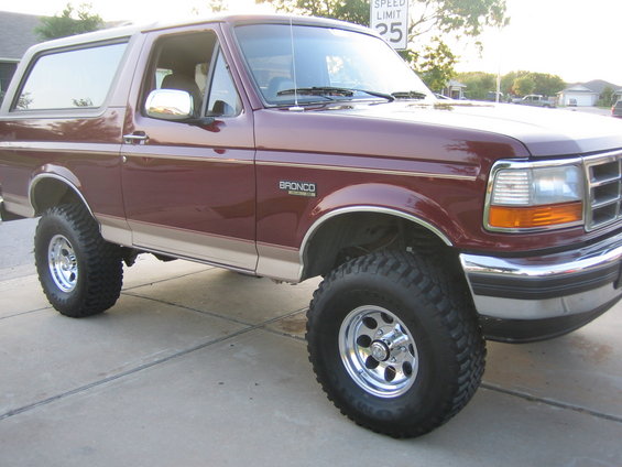 Maroon 1996 Ford Bronco with tan trim and chrome wheels parked on a driveway