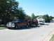 1996 Ford Bronco - A maroon Ford F-250 Super Duty pickup truck tows a trailer carrying two Jeeps and an RV down a suburban street.