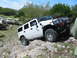 1996 Ford Bronco - A white Hummer H2 is shown off-roading on a rocky slope with other vehicles in the background.