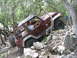 1996 Ford Bronco - A maroon Jeep Wrangler navigates a challenging rocky terrain, with a driver behind the wheel.