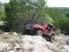 1996 Ford Bronco - A red Jeep Wrangler navigates a challenging rocky trail, demonstrating its off-road capabilities.