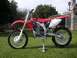 1900 Honda Big Red - A red Honda CRF dirt bike is displayed on a stand outdoors on a sunny day.