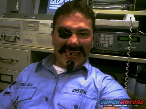 Man with eyepatch, fake mustache, and missing teeth, wearing a blue uniform