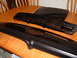 1978 Ford Mustang II - Two black plastic automotive parts, likely a grille and trim, are displayed on a wooden table.