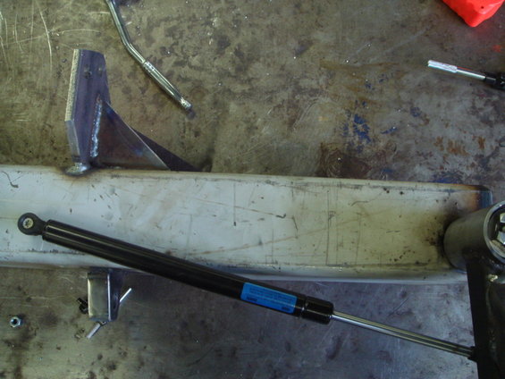 Metal bracket welded to a beam with a black gas strut attached