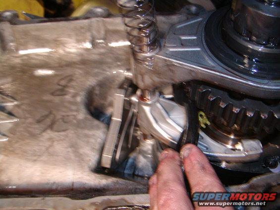 Close-up of transmission gears, spring, and linkage with a hand present