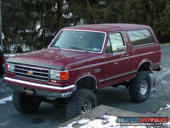 Maroon 1991 Ford Bronco with lifted suspension and large tires parked outdoors
