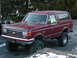 1991 Ford Bronco - Maroon 1991 Ford Bronco, lifted with large off-road tires, sits outside in a snowy environment.