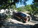 1996 Ford Bronco - A maroon 1996 Ford Bronco navigates a challenging, rocky off-road path under a canopy of trees.