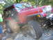 1996 Ford Bronco - Red Jeep Wrangler navigating a rocky trail. Grille design suggests a 1991 model year.
