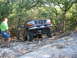 1996 Ford Bronco - A man watches a lifted Ford Bronco navigate a rocky off-road path.