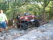 1996 Ford Bronco - An orange Jeep Wrangler navigates a rocky trail, demonstrating its off-road capabilities.
