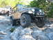 1996 Ford Bronco - Two Jeeps navigate a rocky trail with dense trees in the background.