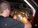 1989 Lincoln Town Car - A mechanic works on the exposed dashboard wiring of a vehicle, illuminated by a work light.