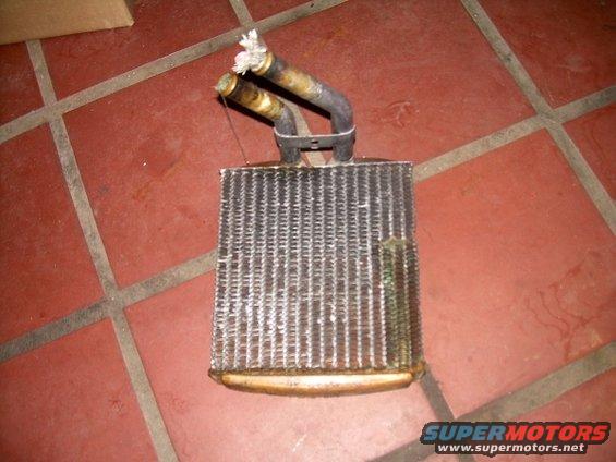 Heater core with two bent metal tubes, one with frayed rope. The fins are dirty and corroded
